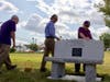 Friends and family of Ken Roos, who passed away in 2018, lay rocks on a new granite bench installed at the SEA/SEUI Local 1984 headquarters on North Main Street in Concord on Aug. 10.
