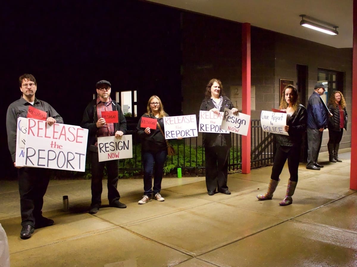 Protesters outside of the Mill Brook School in Concord Monday called for the district's assistant superintendent to resign. 