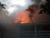 A Concord firefighter uses a chainsaw to cut open the side of an apartment building fire on South Street in the South End of Concord on Sept. 23.