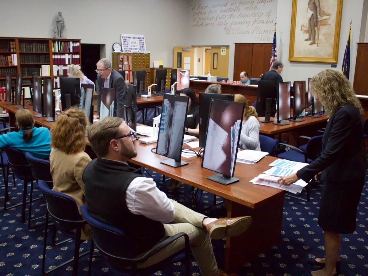 ​State representative candidates, state officials, and volunteers wait for ballots to be prepared for a recount on Sept. 19 at the state archives building in Concord.