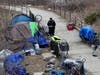 A Concord police officer canvasses the massive homeless camp at Healy Memorial Park on March 20, looking for information about a man who jumped from the Manchester Street Bridge. 
