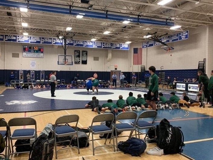 Enfield and Rocky Hill wrestlers line the edges of the mat during a special Senior Night match in Rock Grove, Connecticut, Wednesday.