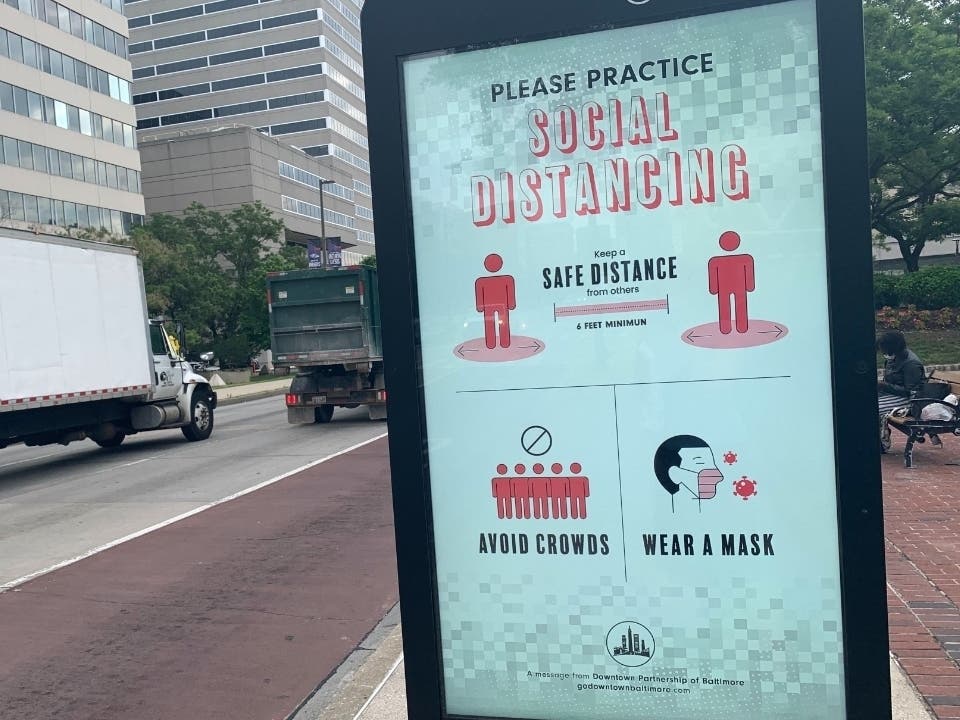 A sign on Pratt Street in downtown Baltimore encourages people to avoid crowds, wear a mask and stay 6 feet apart in the interest of public health.
