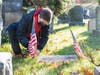 Robert Del Vecchio placing a flag on the grave of veteran James DeMilia in the Sleepy Hollow Cemetery