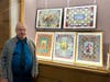 Aaron Needle poses with his art display at the Waltham Public Library