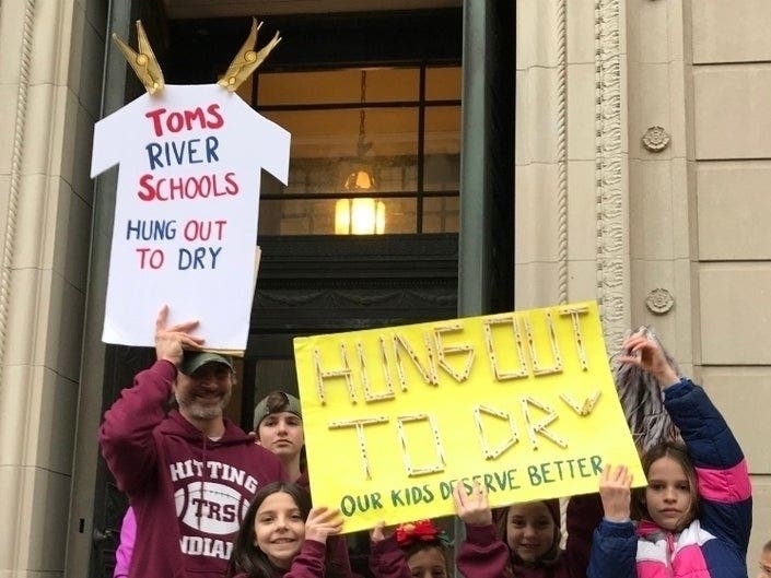 A father holds up a sign during the Toms River rally in Trenton, highlighting a comment Gov. Phil Murphy made to a Toms River parent Nov. 21 on the "Ask the Governor" show.