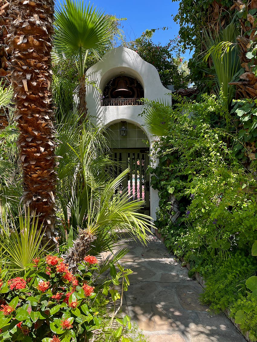 Spanish bell tower with green spindles, lush garden