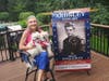 Sharon Colabello, the lead organizer of the Ardsley initiative, and the unfurled banner of her late father Martin Engleman, decorated World War II veteran. She holds the "grand pups" her father loved.