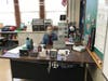 ICGS 2nd grade teacher, Miss Erin Kennedy sits at her desk which is equipped with a plexiglass shield. 