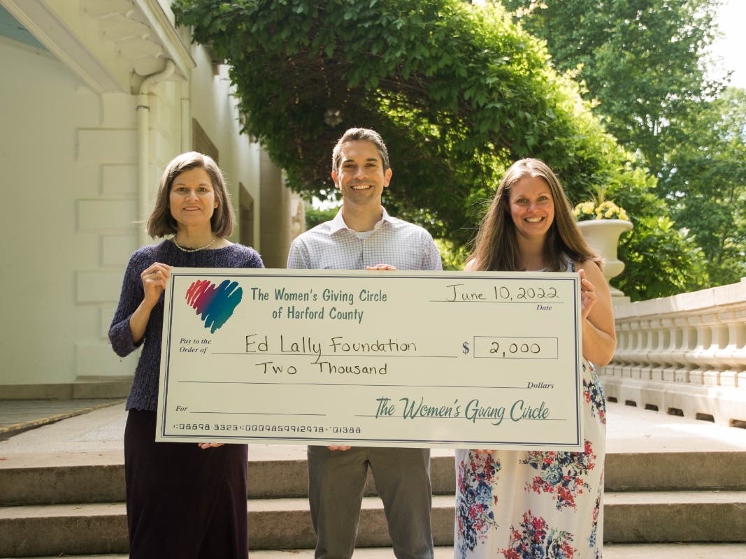 Donna Kreis, chair of the Women's Giving Circle of Harford County, and Sara Burley, co-chair of the Grant Committee, present a grant to Jordan Lally, co-founder of the Ed Lally Foundation, to support the Harford County Women's Mindfulness Retreat. 