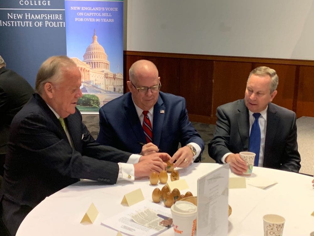 Gov. Larry Hogan (center) signs wooden eggs on Tuesday at "Politics & Eggs," a political breakfast in New Hampshire.