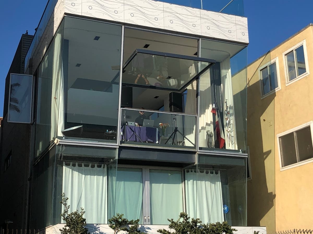 A deejay plays an outdoor show from an apartment above the boardwalk in Venice Beach.