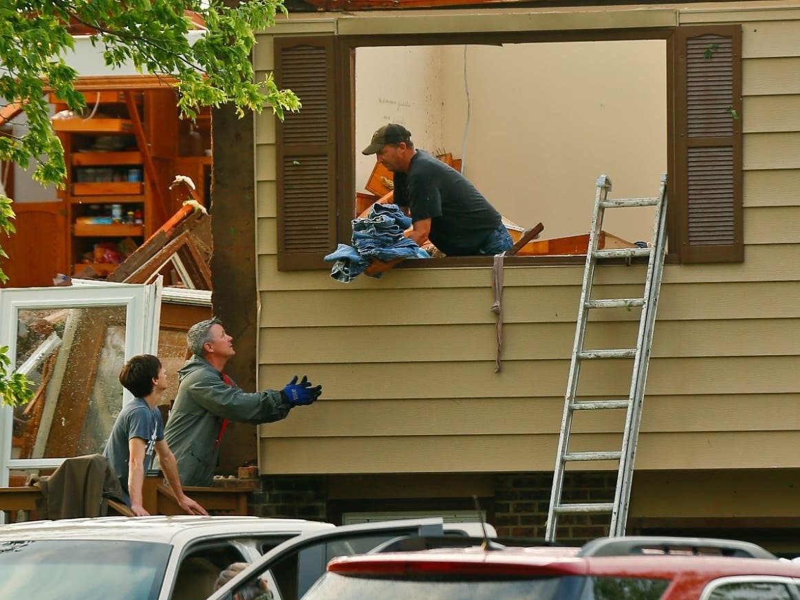 A man passes off a bundle of blue jeans after his home near Lawrence, Kansas, was hit by a tornado Tuesday.