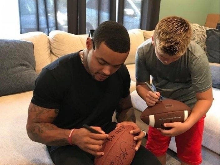 Two-time Super Bowl champion Jonathan Csillas of the New York Giants autographs a football to replace one 10-year-old Joey Cirillo lost at a Toms River, New Jersey, football game. 