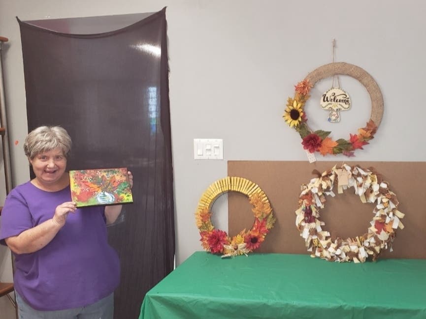 An artist with Community Services Foundation holds up work she created. 