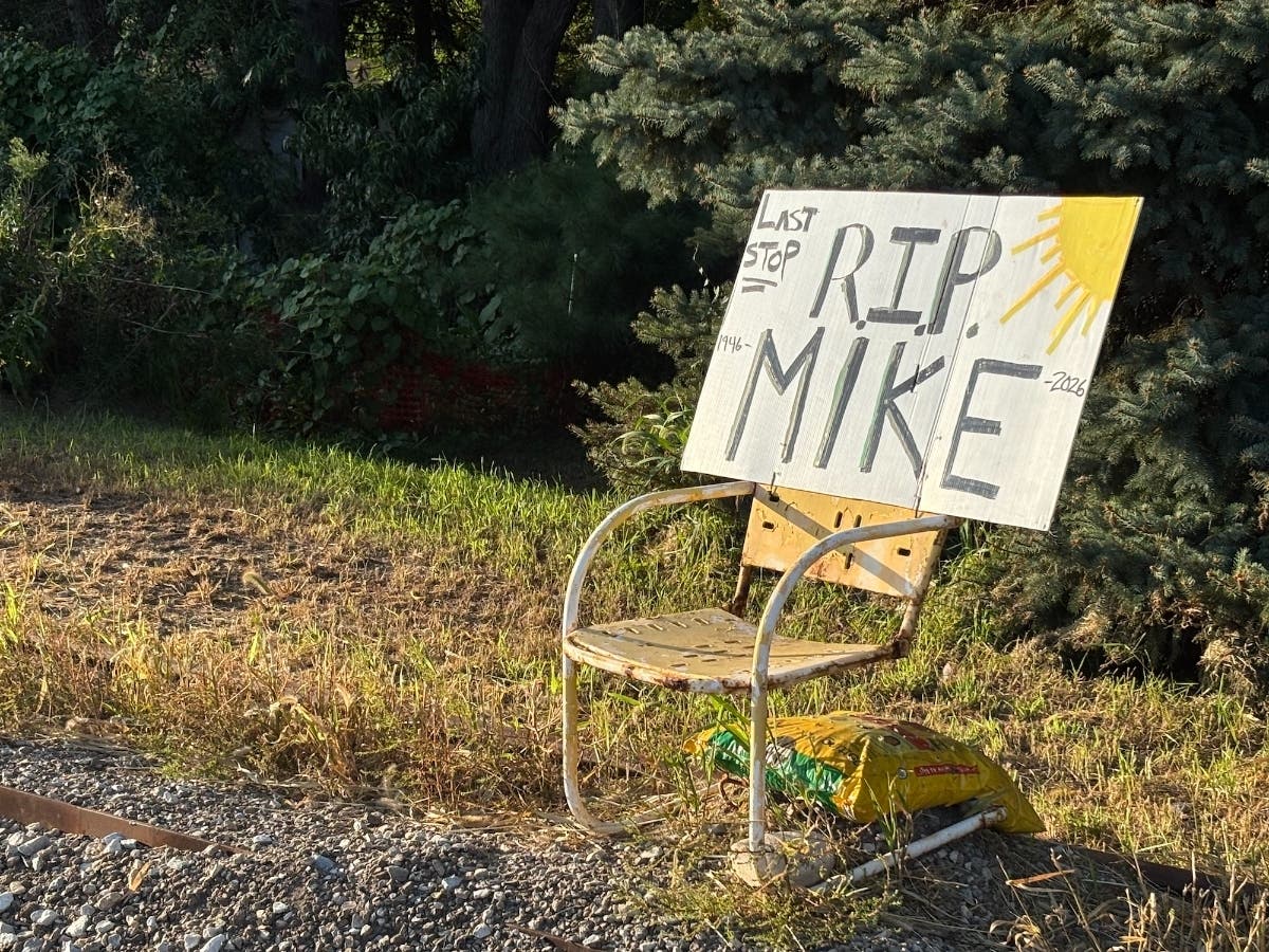 An "RIP Mike" sign sits on a yellow chair, similar to the one where Mike Buell used to sit and watch the trains pass.