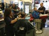 Ann Marie Vaccarella (far left) and Paul Smith cut hair at Barber Serville. The business will close next month.