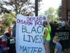 Protesters hold a Black Lives Matter banner outside the police station.