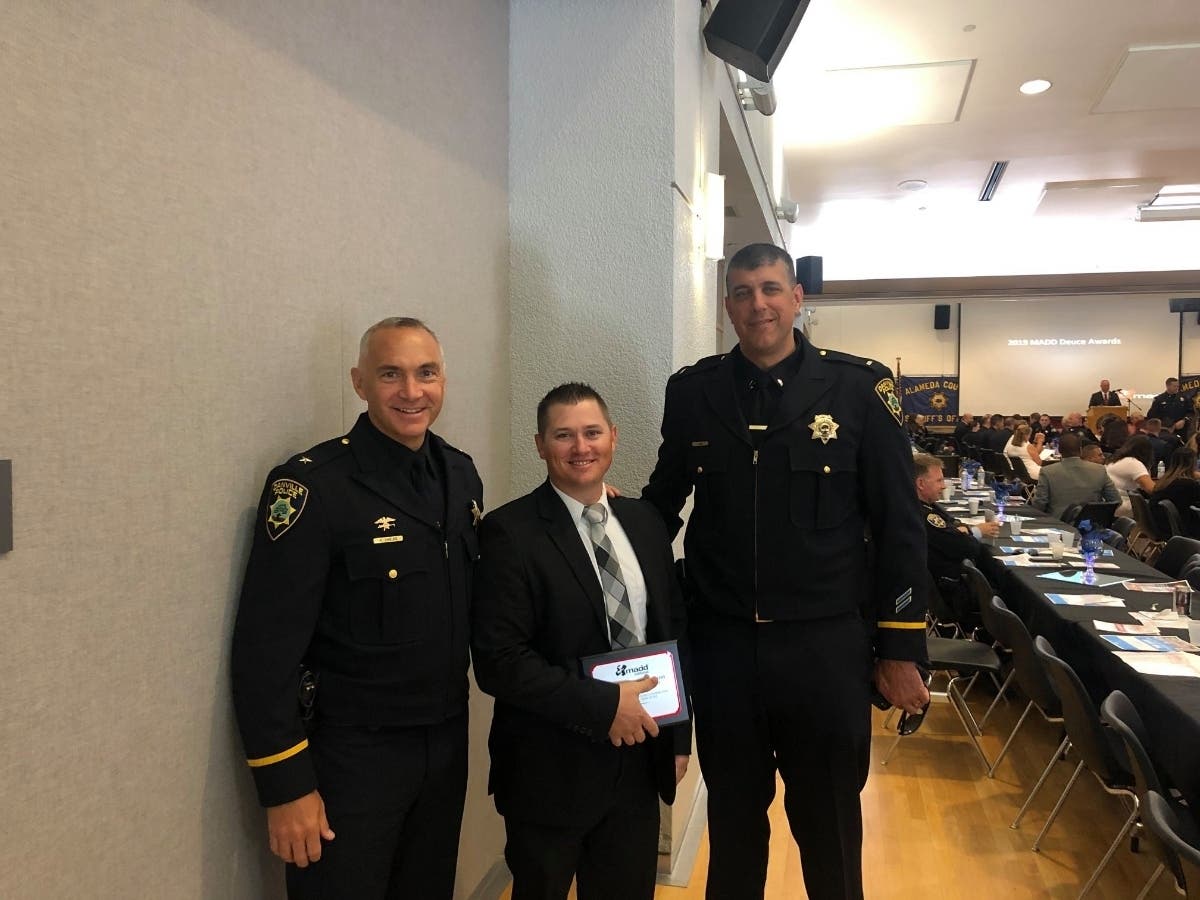 Officer James Adams is flanked by Chief Allan Shields (left) and Lt. Doug Muse.
