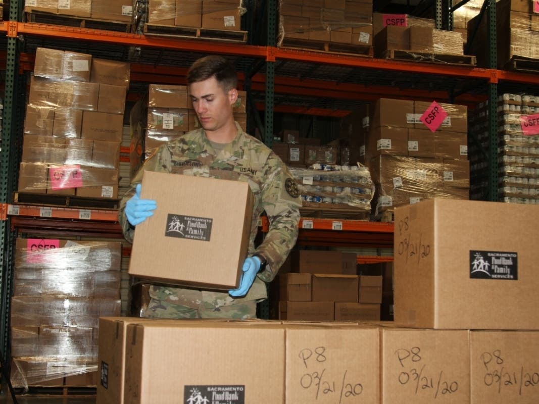 In this file image, U.S. Army Spc. Colby Chiverton of the California Army National Guard's 115th Regional Support Group lines up food boxes March 21 at the Sacramento Food Bank & Family Services outlet in Sacramento, California. 
