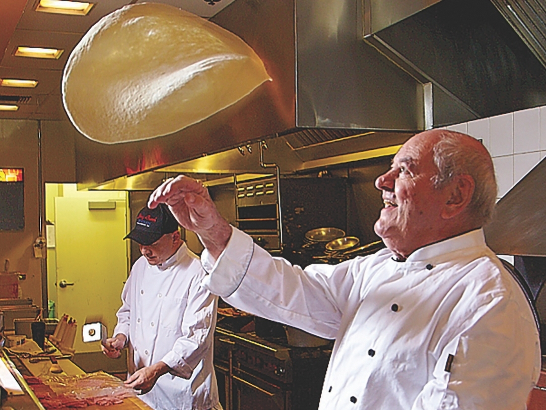 Restaurant founder Johnny Costa throws pizza dough. Born in Naples, Italy, he was 87 at the time of his 2019 passing. His family continues to operate his eatery.