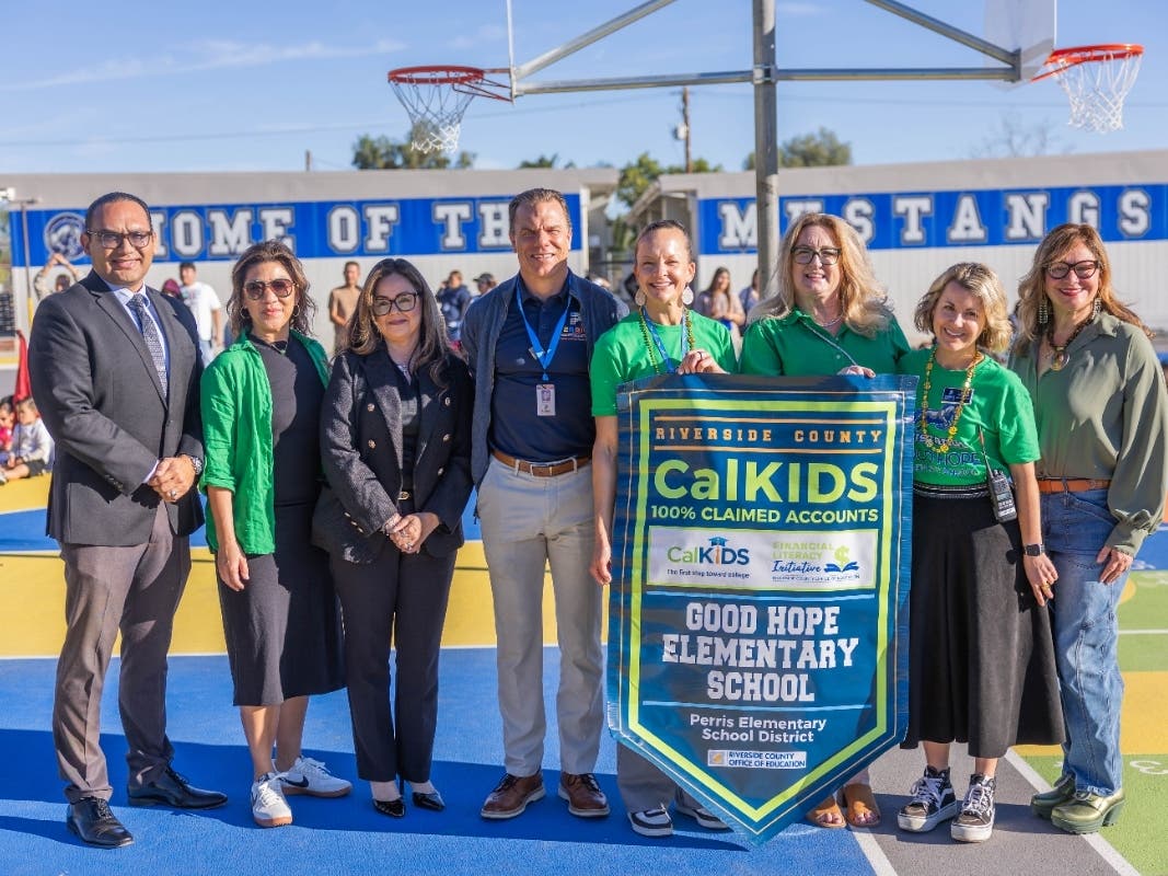 Riverside County Superintendent of Schools Dr. Edwin Gomez presents a banner celebrating 100% claimed CalKIDS accounts to educators in the Perris Elementary School District on March 13.